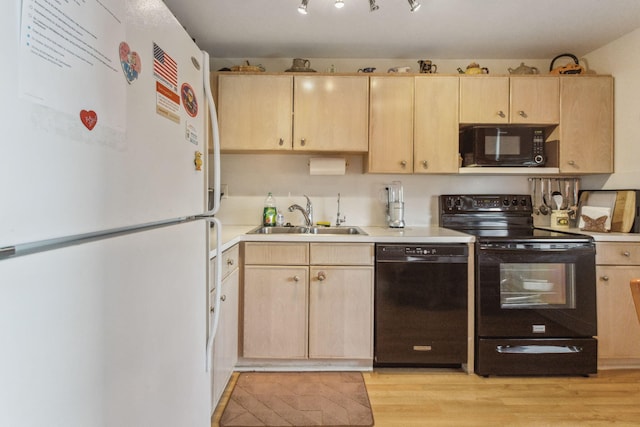 kitchen with black appliances, light brown cabinets, a sink, light countertops, and light wood-type flooring
