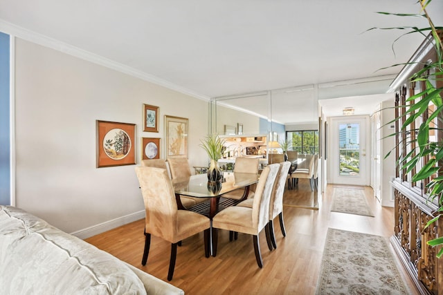 dining space with crown molding, wood finished floors, and baseboards