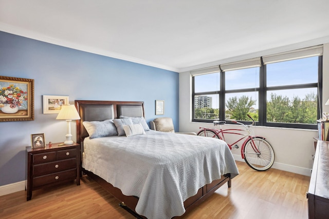 bedroom with wood finished floors, baseboards, and crown molding