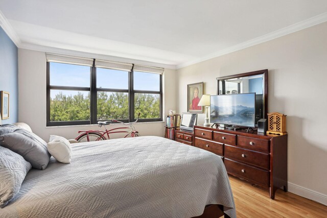 bedroom featuring ornamental molding, light wood finished floors, and baseboards
