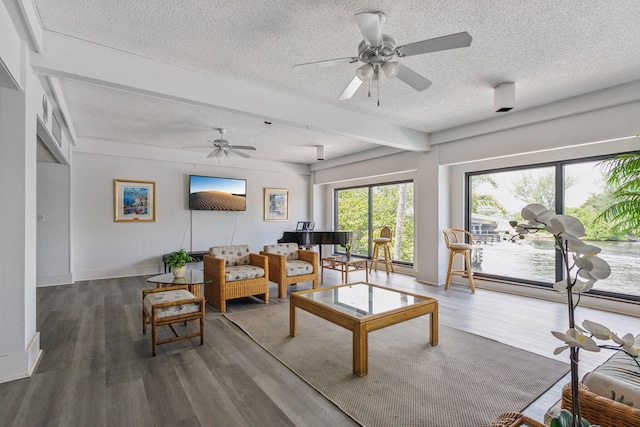 living room featuring wood finished floors, a textured ceiling, beamed ceiling, and a ceiling fan