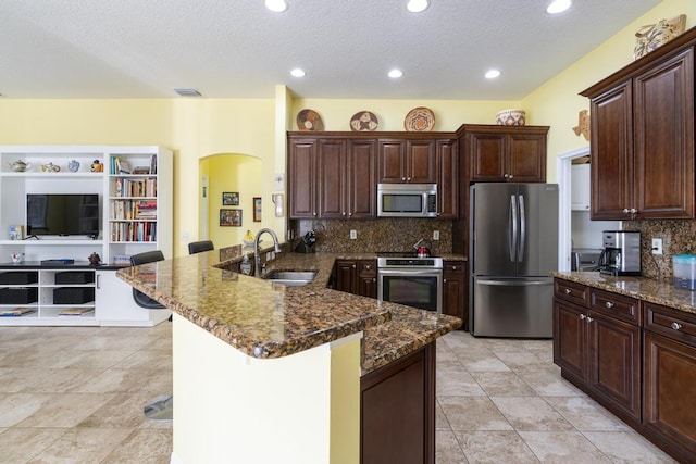 2904 SW Sutton Pl, Palm City, FL 34990 - kitchen with appliances with stainless steel finishes, a sink, a peninsula, arched walkways, and decorative backsplash