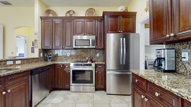 2904 SW Sutton Pl, Palm City, FL 34990 - kitchen featuring appliances with stainless steel finishes, backsplash, dark brown cabinets, and light stone counters