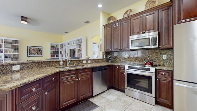 2904 SW Sutton Pl, Palm City, FL 34990 - kitchen with appliances with stainless steel finishes, a sink, tasteful backsplash, a peninsula, and light stone counters