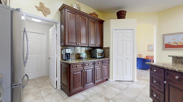 2904 SW Sutton Pl, Palm City, FL 34990 - kitchen featuring freestanding refrigerator, light stone countertops, backsplash, and light tile patterned floors