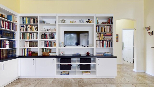 2904 SW Sutton Pl, Palm City, FL 34990 - sitting room featuring arched walkways, wall of books, and baseboards