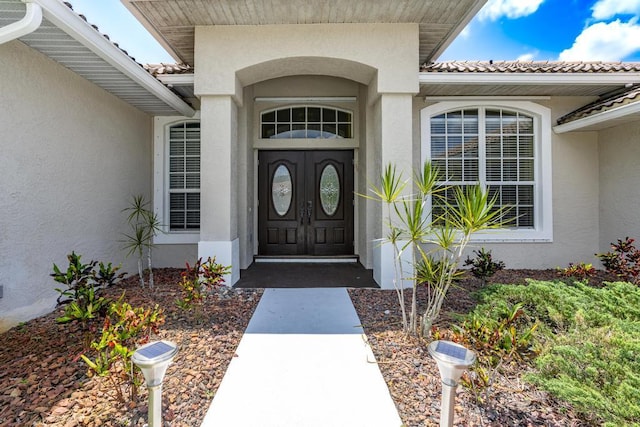 2904 SW Sutton Pl, Palm City, FL 34990 - view of exterior entry with stucco siding and a tile roof