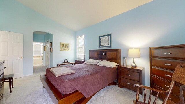 2904 SW Sutton Pl, Palm City, FL 34990 - bedroom with arched walkways, light colored carpet, baseboards, ensuite bath, and vaulted ceiling