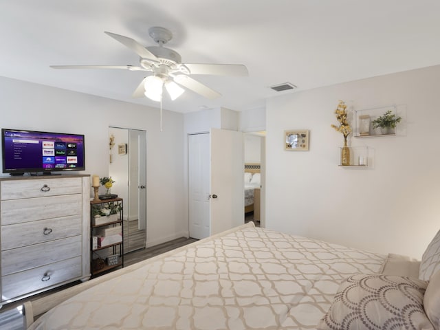 bedroom with ceiling fan, wood finished floors, and a closet
