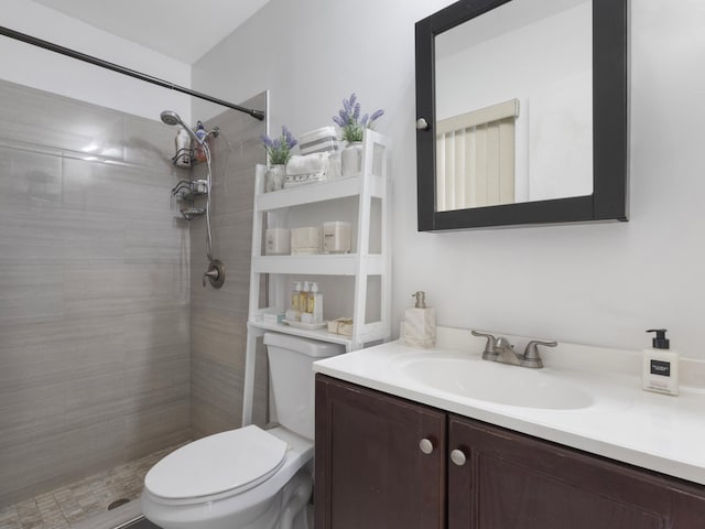 bathroom featuring toilet, vanity, and a tile shower