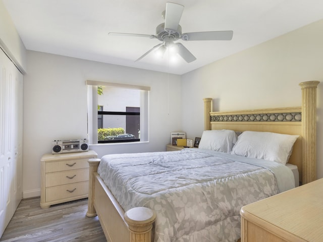 bedroom with wood finished floors, a closet, a ceiling fan, and baseboards