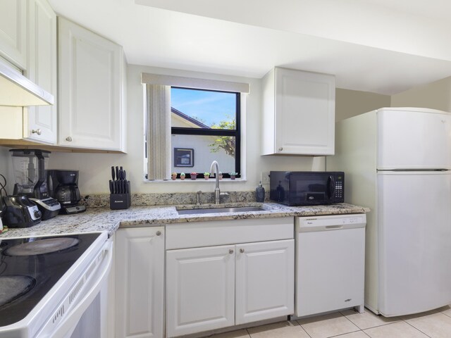 kitchen featuring white appliances, a sink, white cabinets, light tile patterned flooring, and under cabinet range hood