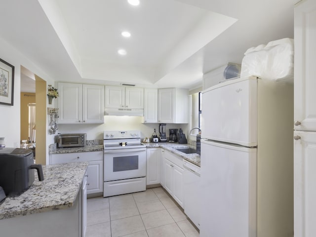 kitchen featuring white appliances, a sink, a tray ceiling, white cabinetry, and under cabinet range hood