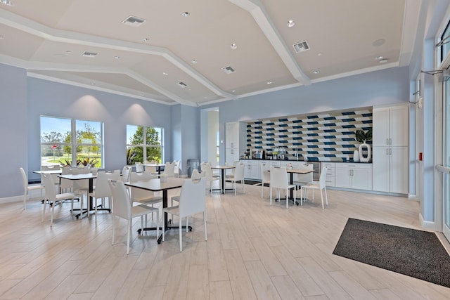 dining area featuring light wood-style floors, recessed lighting, baseboards, and a high ceiling