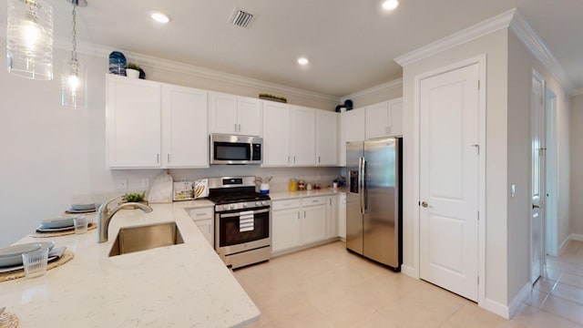 kitchen featuring appliances with stainless steel finishes, a sink, white cabinets, ornamental molding, and pendant lighting
