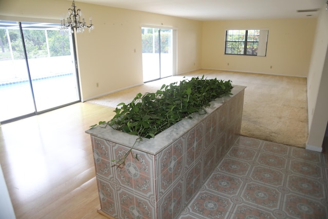 unfurnished room featuring light colored carpet, plenty of natural light, a chandelier, and baseboards