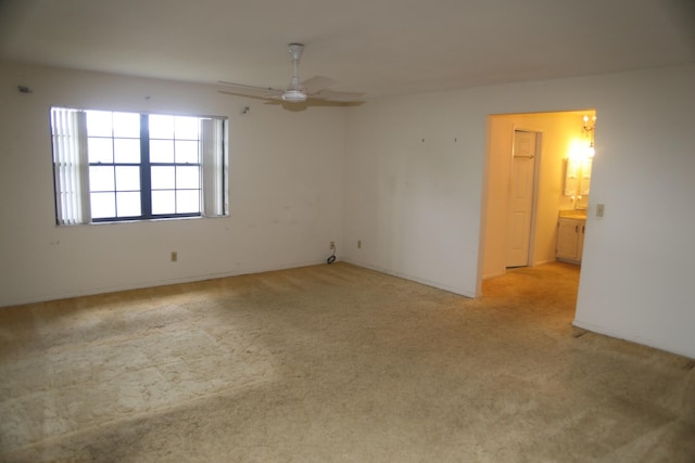 spare room with light colored carpet and a ceiling fan