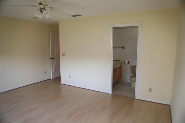 unfurnished bedroom with light wood finished floors, baseboards, and ensuite bathroom