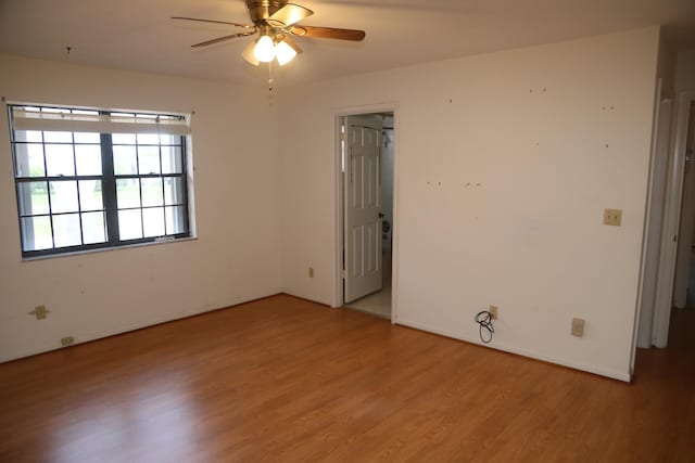 spare room with light wood-type flooring, a ceiling fan, and baseboards