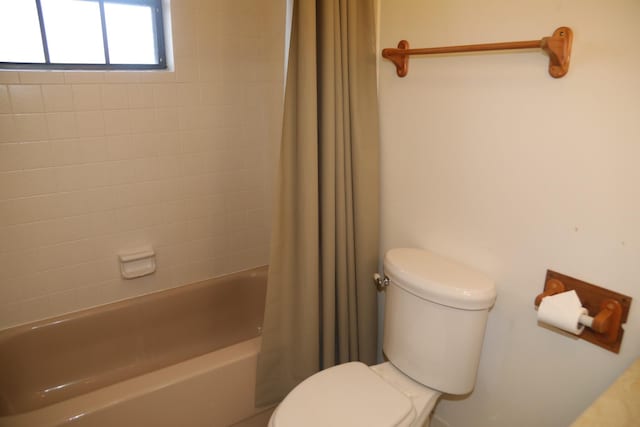 bathroom featuring toilet and shower / tub combo with curtain