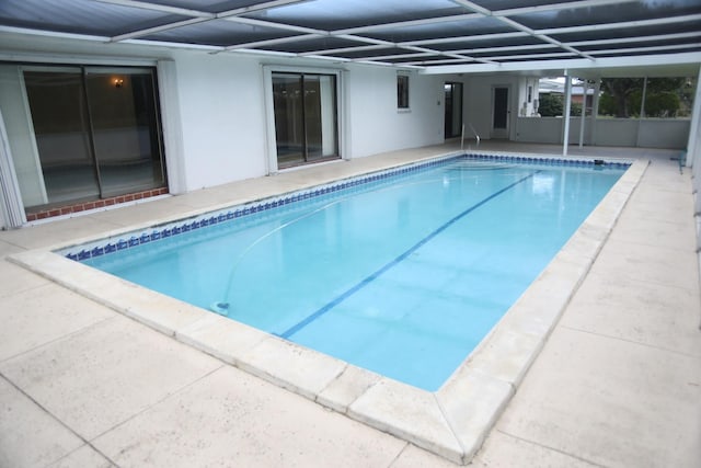 swimming pool with glass enclosure and a patio