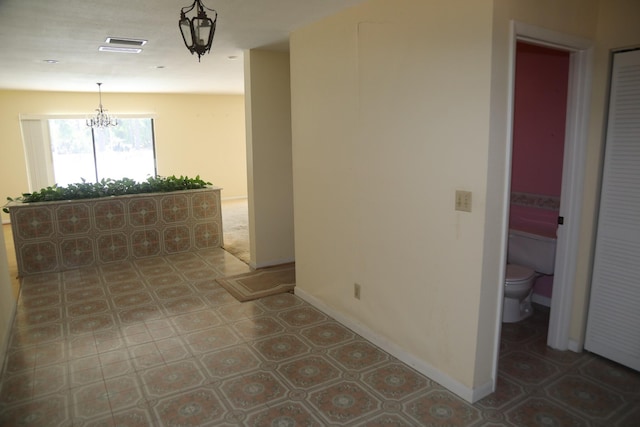 spare room with a chandelier, light flooring, and baseboards