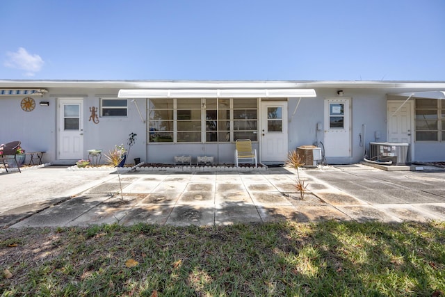 rear view of property featuring a patio area, central air condition unit, and stucco siding