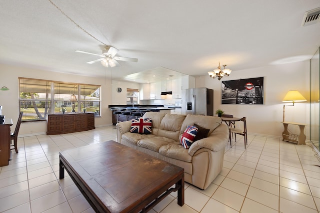living room featuring light tile patterned floors, a chandelier, a ceiling fan, and baseboards