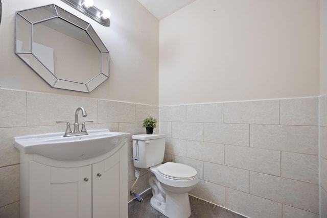 bathroom with vanity, toilet, a wainscoted wall, tile walls, and wood finished floors
