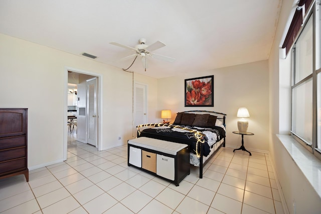 bedroom featuring multiple windows, a ceiling fan, baseboards, and light tile patterned floors