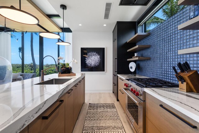 kitchen with high end stove, a sink, open shelves, light wood-style floors, and modern cabinets