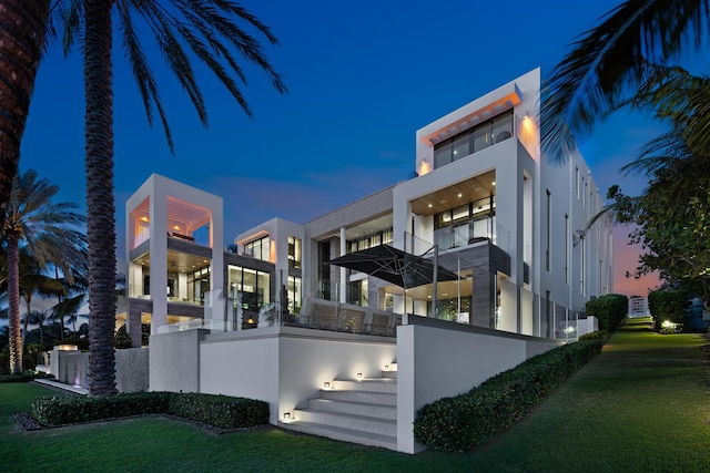 back of property featuring stucco siding and a lawn