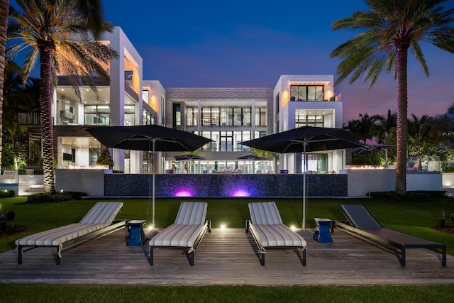 back of property featuring a balcony, a yard, and stucco siding