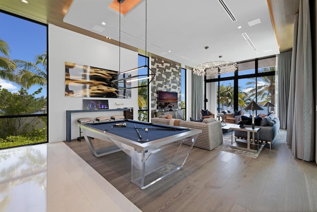 playroom with floor to ceiling windows, a chandelier, pool table, and wood finished floors