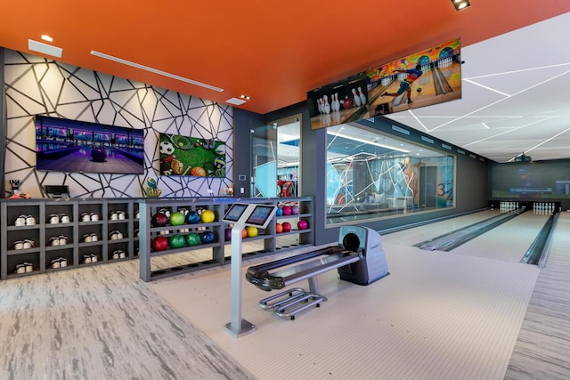playroom with a bowling alley, wood finished floors, and a paneled ceiling