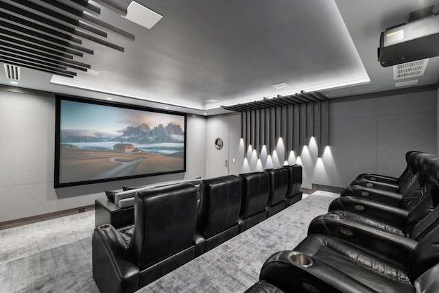 home theater room featuring a tray ceiling and baseboards