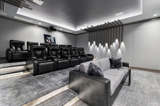 carpeted home theater room with a tray ceiling, a decorative wall, and recessed lighting