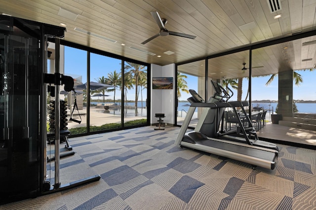 exercise room featuring a wall of windows, a water view, carpet floors, and ceiling fan