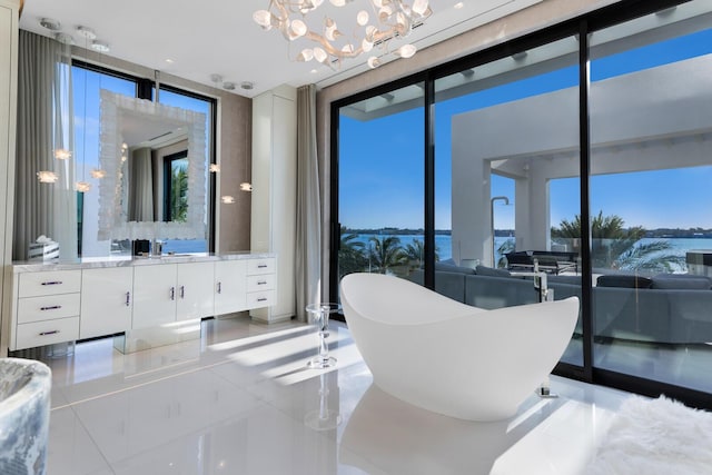 full bathroom with a wall of windows, a soaking tub, healthy amount of natural light, tile patterned flooring, and a chandelier