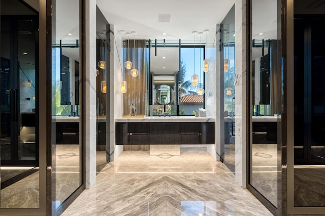 bathroom featuring marble tiled flooring, vanity, and a wall of windows
