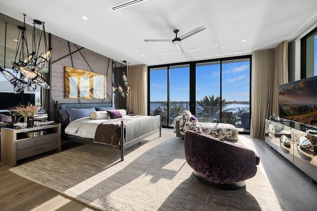 bedroom featuring expansive windows, wood finished floors, a chandelier, and a ceiling fan