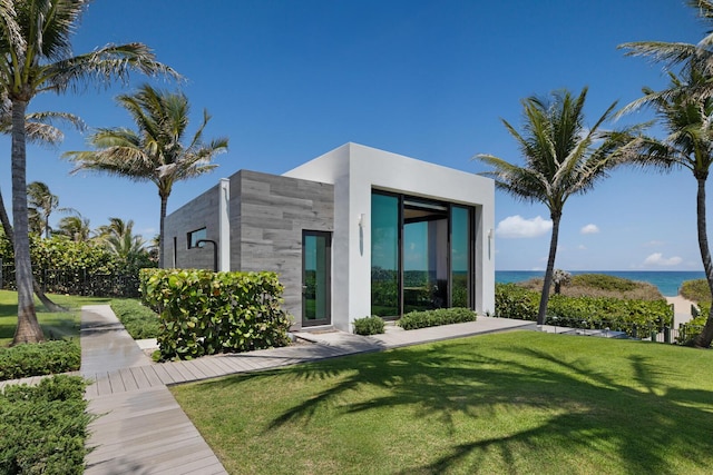 back of house featuring a yard, a water view, and stucco siding