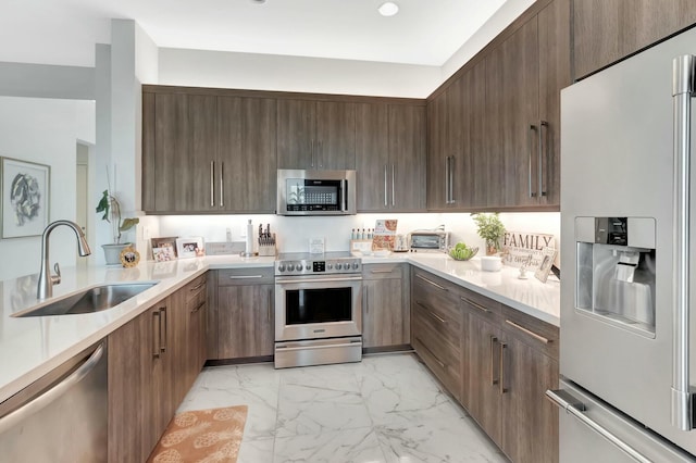 kitchen featuring stainless steel appliances, a sink, modern cabinets, light countertops, and recessed lighting