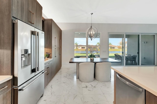 kitchen with stainless steel appliances, light marble finish floors, light countertops, a chandelier, and pendant lighting