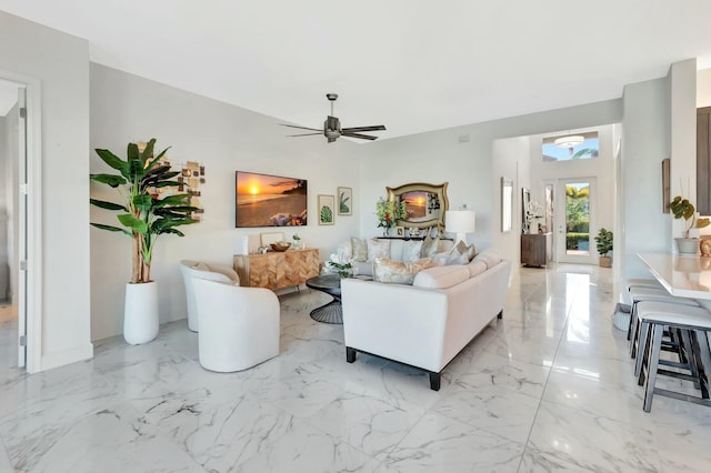 living area featuring light marble finish flooring and ceiling fan
