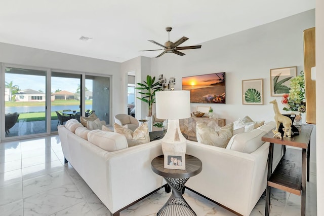 living area with light marble finish floors, a ceiling fan, and a water view