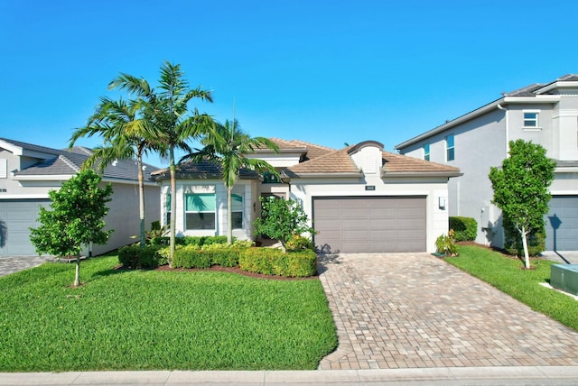 view of front of house with a front lawn, an attached garage, decorative driveway, stucco siding, and a tiled roof