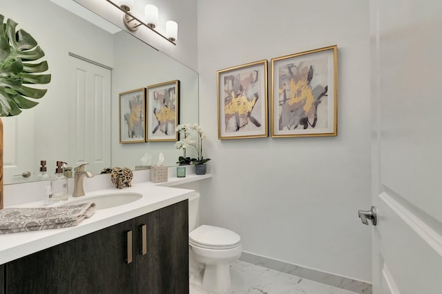 bathroom with marble look tiles, toilet, vanity, and baseboards