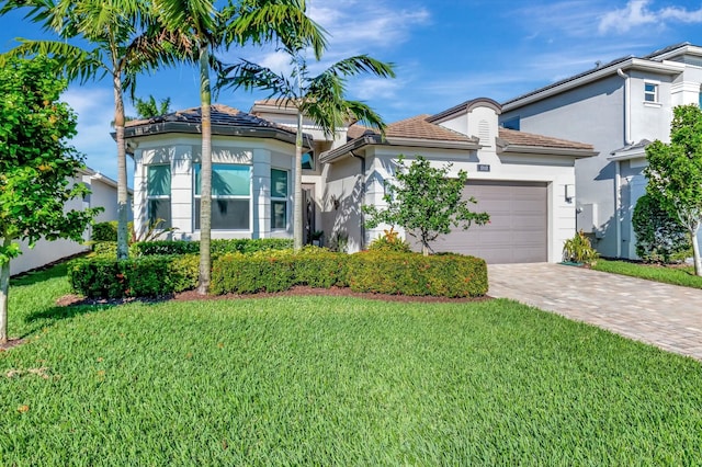 view of front of property with stucco siding, a garage, a front yard, and decorative driveway