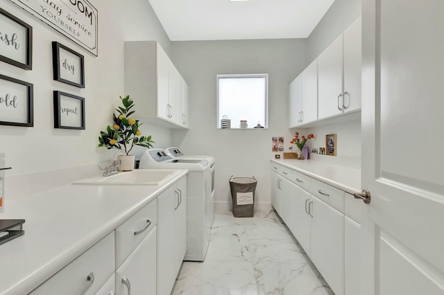 washroom with light marble finish floors, washing machine and dryer, cabinet space, and baseboards